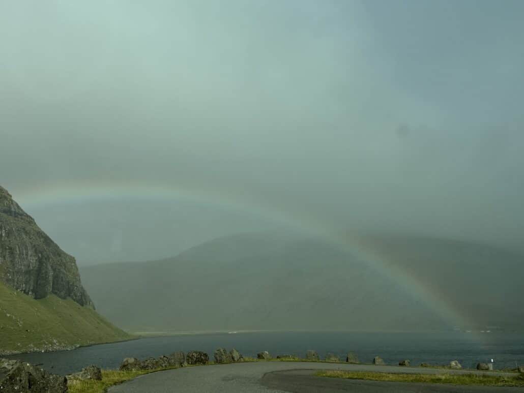 Regenbogen in einer nebligen Bucht mit vielen Grünschattierungen