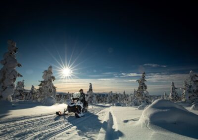 Person auf Schneemobil fährt durch winterliche Waldlandschaft