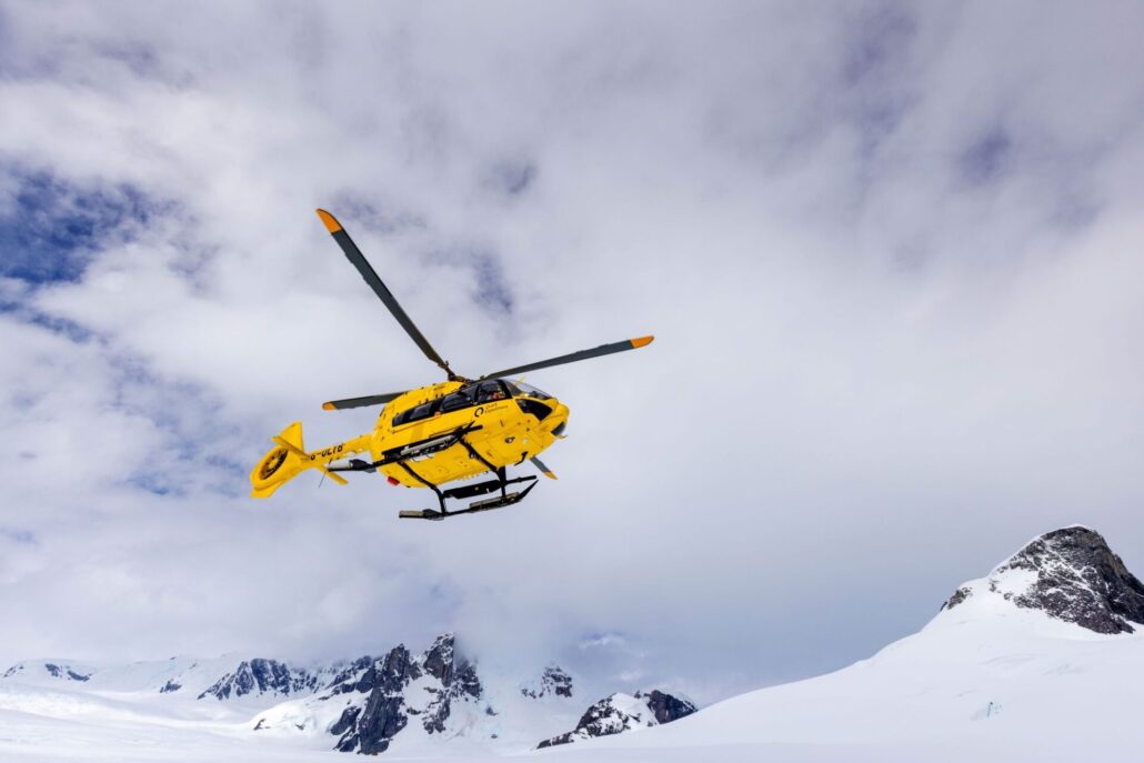 Ein gelber Helikopter über verschneiter Landschaft