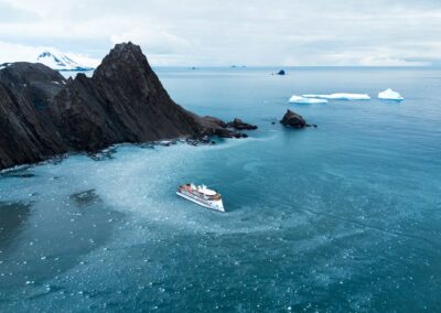 A bird's-eye view of an expedition ship among drift ice in a bay