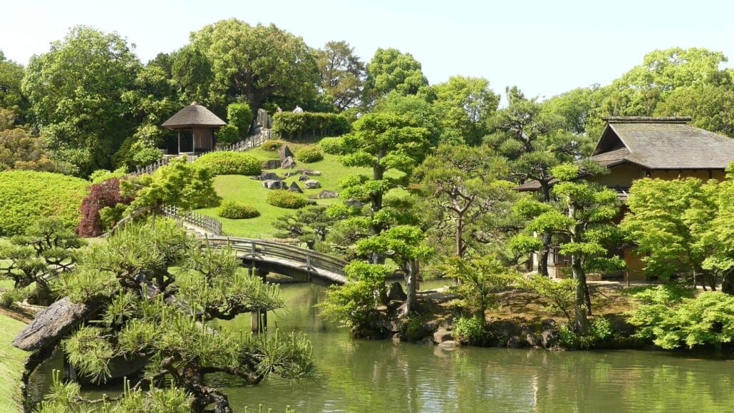 Japanische Gartenlandschaft mit Wasser und gebogener Brücke