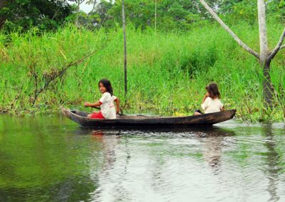 Two children in a traditional canoe on a riverbank