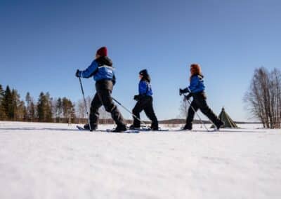Drei Personen sind mit Schneeschuhen in der verschneiten Landschaft unterwegs