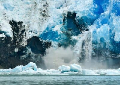 Von einem Gletscher bricht Eis ab und fällt ins Meer.