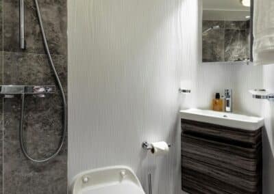 Kleines Bad mit Waschbecken, Toilette und offener Dusche