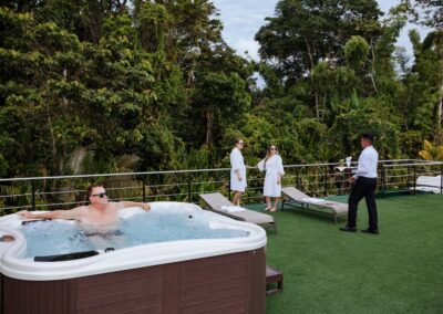 Whirlpool auf dem Außendeck eines Schiffs. Ein Mann sitzt darin, drei weitere Personen im Hintergrund.