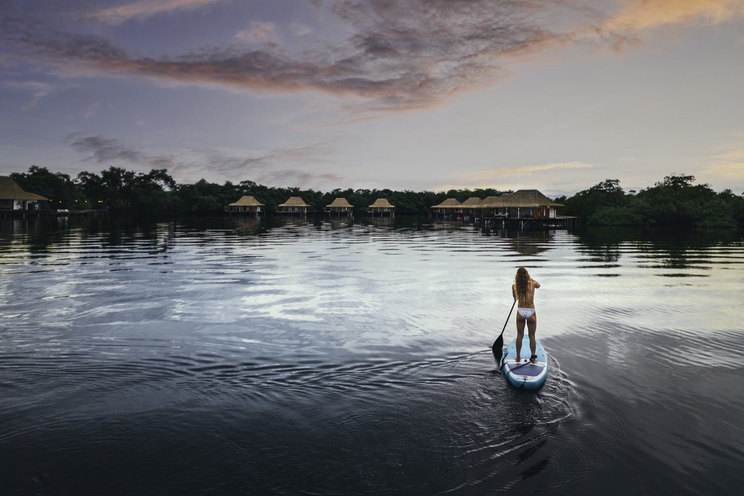 Stand-up-Paddler auf tuerkisem Wasser vor tropischer Kueste in Bocas del Toro Panama