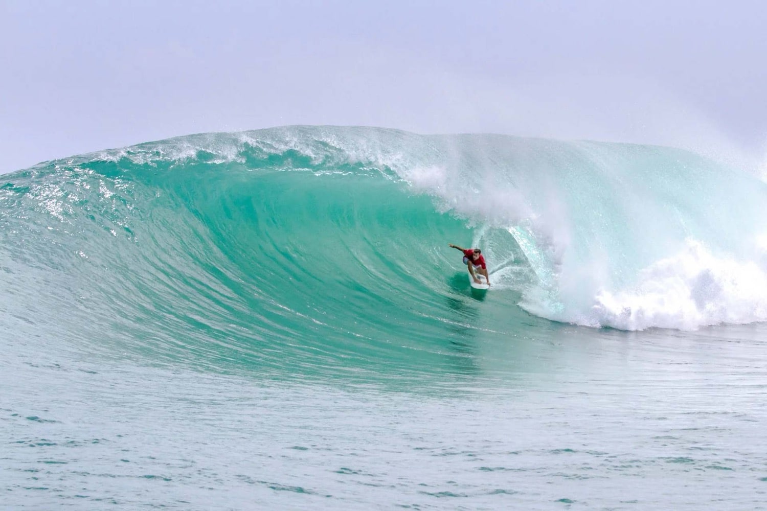 Surfer in tuerkiser Welle vor der karibischen Kueste von Bocas del Toro Panama
