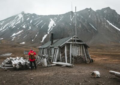 Verlassene Trapperhütte vor schneebedeckten Bergen in Spitzbergen