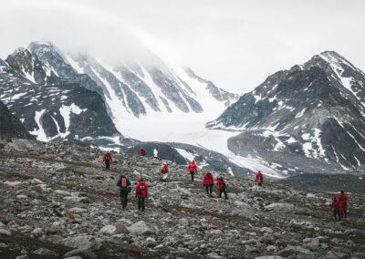 Wandergruppe auf einer Anhöhe mit Blick auf einen Gletscher in Spitzbergen