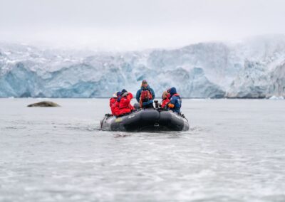 Zodiac vor einer Gletscherfront mit Bartrobbe auf einer Eisscholle in Spitzbergen