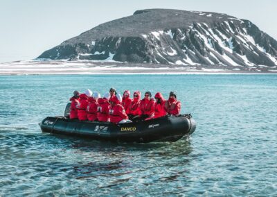 Zodiac fährt durch türkisfarbenes Schmelzwasser vor einem Gletscher in Spitzbergen