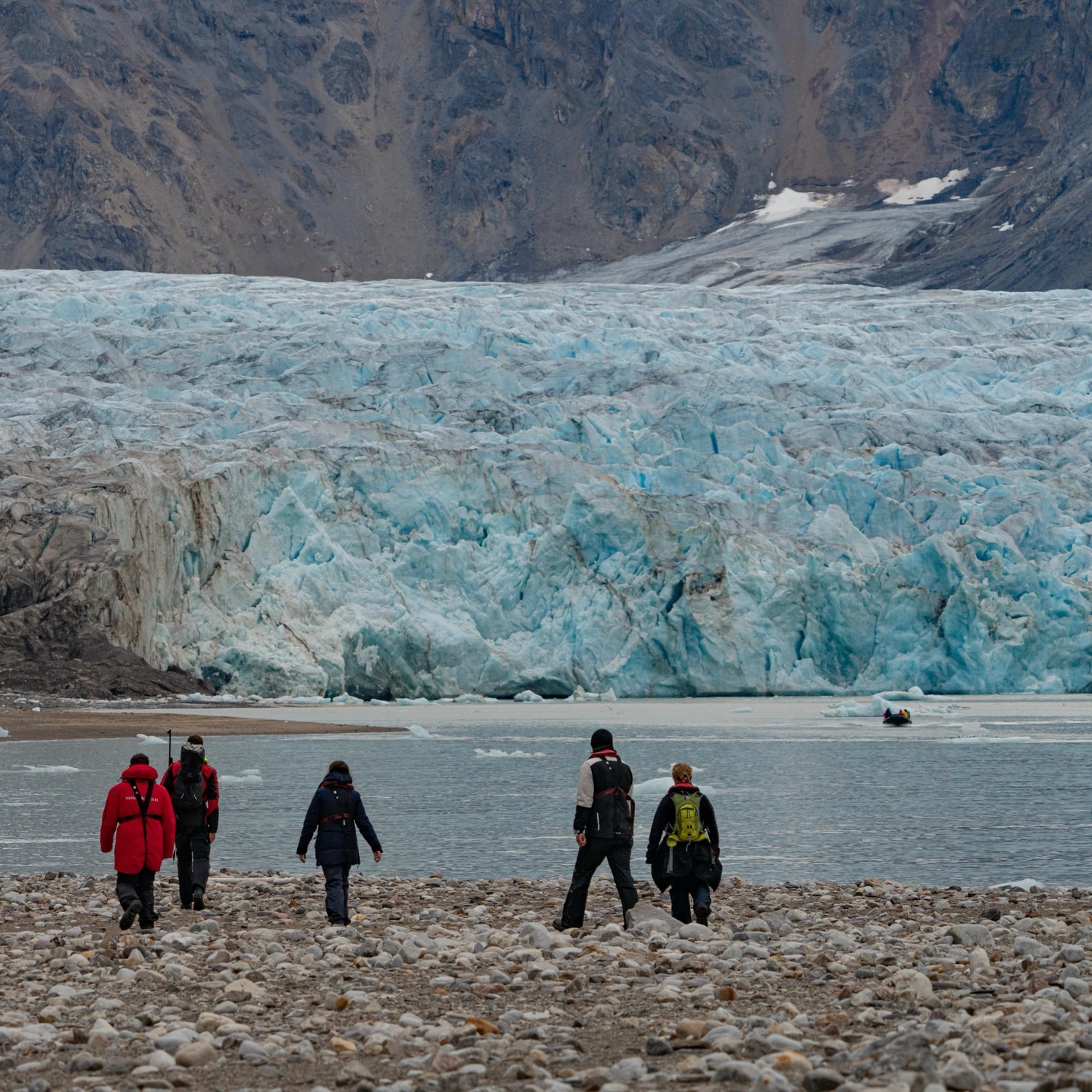 Wandergruppe an einem Strand vor einer großen Gletscherwand auf Spitzbergen