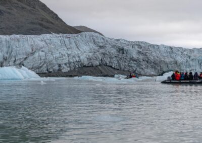 Zodiac mit Expeditionsgästen vor einer kalbenden Gletscherfront im Isfjorden