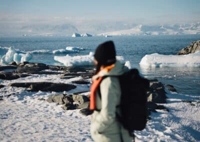 Person mit Rucksack blickt auf Eisbergbucht der Antarktischen Halbinsel