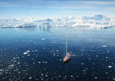 Polar-Segelyacht spiegelt sich auf glattem Wasser zwischen Eisstücken