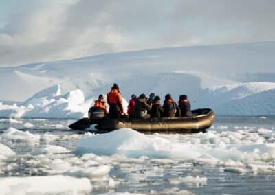 Zodiac mit Passagieren navigiert zwischen Eisschollen vor Bergpanorama
