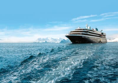 Expeditionsschiff in Fahrt vor schneebedeckten Antarktis-Bergen
