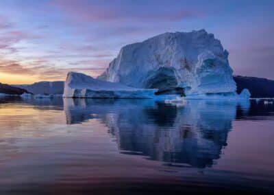 Eisberg im pastellfarbenen Sonnenuntergang mit Spiegelung