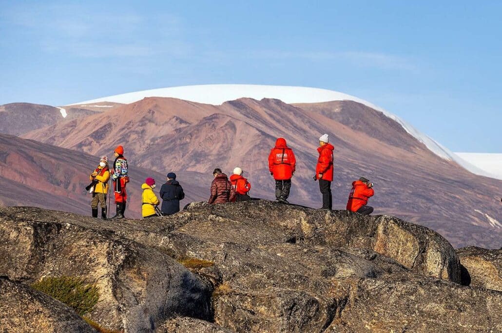 Hiking group on a rocky plateau with a snow-covered mountain panorama