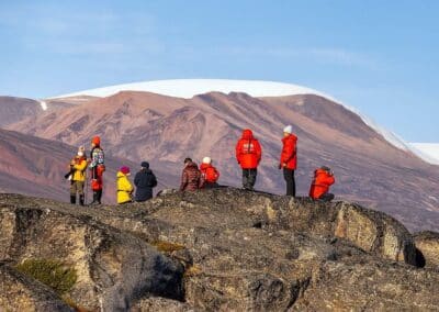 Wandergruppe auf Felsplateau mit schneebedecktem Bergpanorama