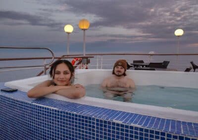 Zwei Gäste im Whirlpool auf dem Sonnendeck bei Sonnenuntergang