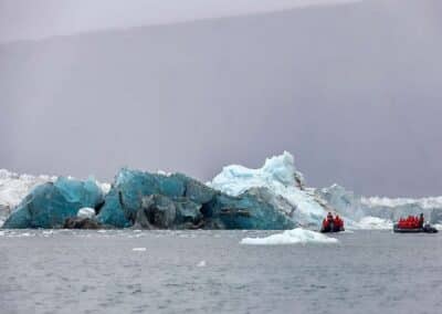 Zwei Zodiacs vor türkis-blauer Gletscherkante mit Eisbergen