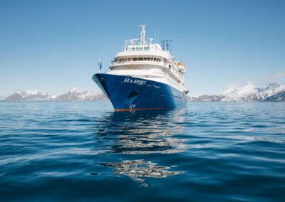 MS Sea Spirit ankert in einer ruhigen arktischen Bucht vor schneebedeckten Bergen