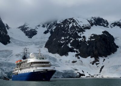 MS Sea Spirit vor steilen Gletscherbergen, daneben ein Zodiac