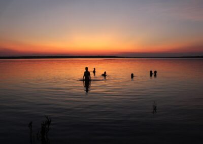 Gäste stehen im flachen Wasser des Amazonas im Abendlicht