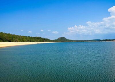 Weiter Sandstrand am Fluss vor bewaldeten Hügeln