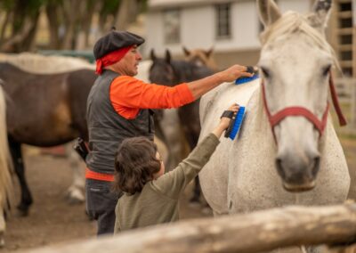Gaucho und Kind striegeln ein Pferd der Estancia