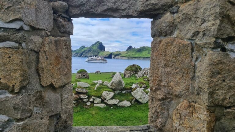 Blick durch ein altes Croft-Fenster auf das Expeditionsschiff in der Bucht von St Kilda
