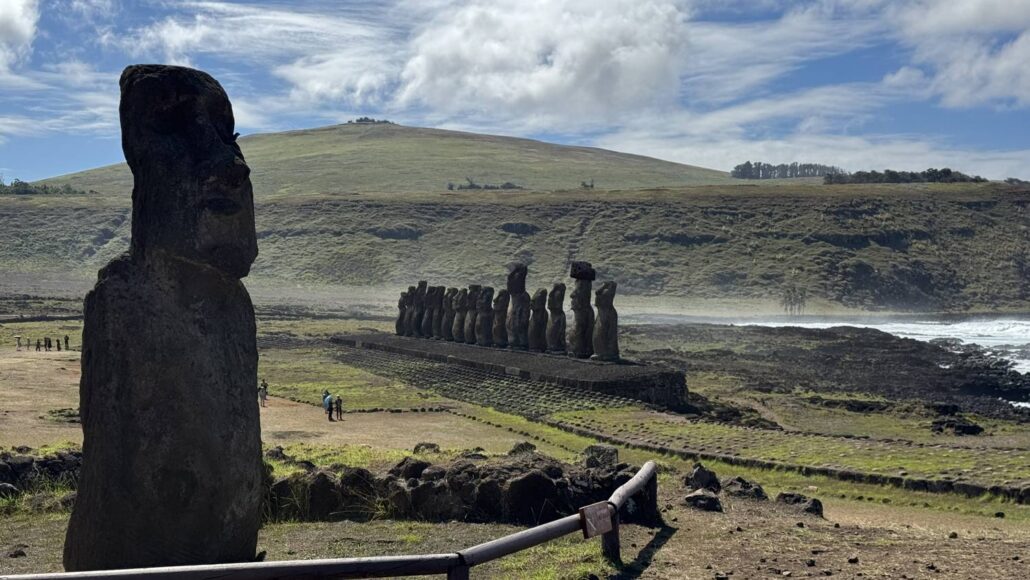 Einzelner Moai im Vordergrund, dahinter die fünfzehn Moai von Ahu Tongariki am Meer