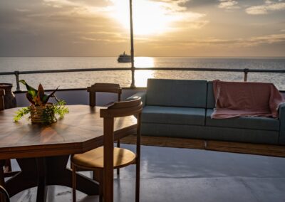 Lounge area on the deck of the Amazon Dolphin with a sofa and dining table at sunset