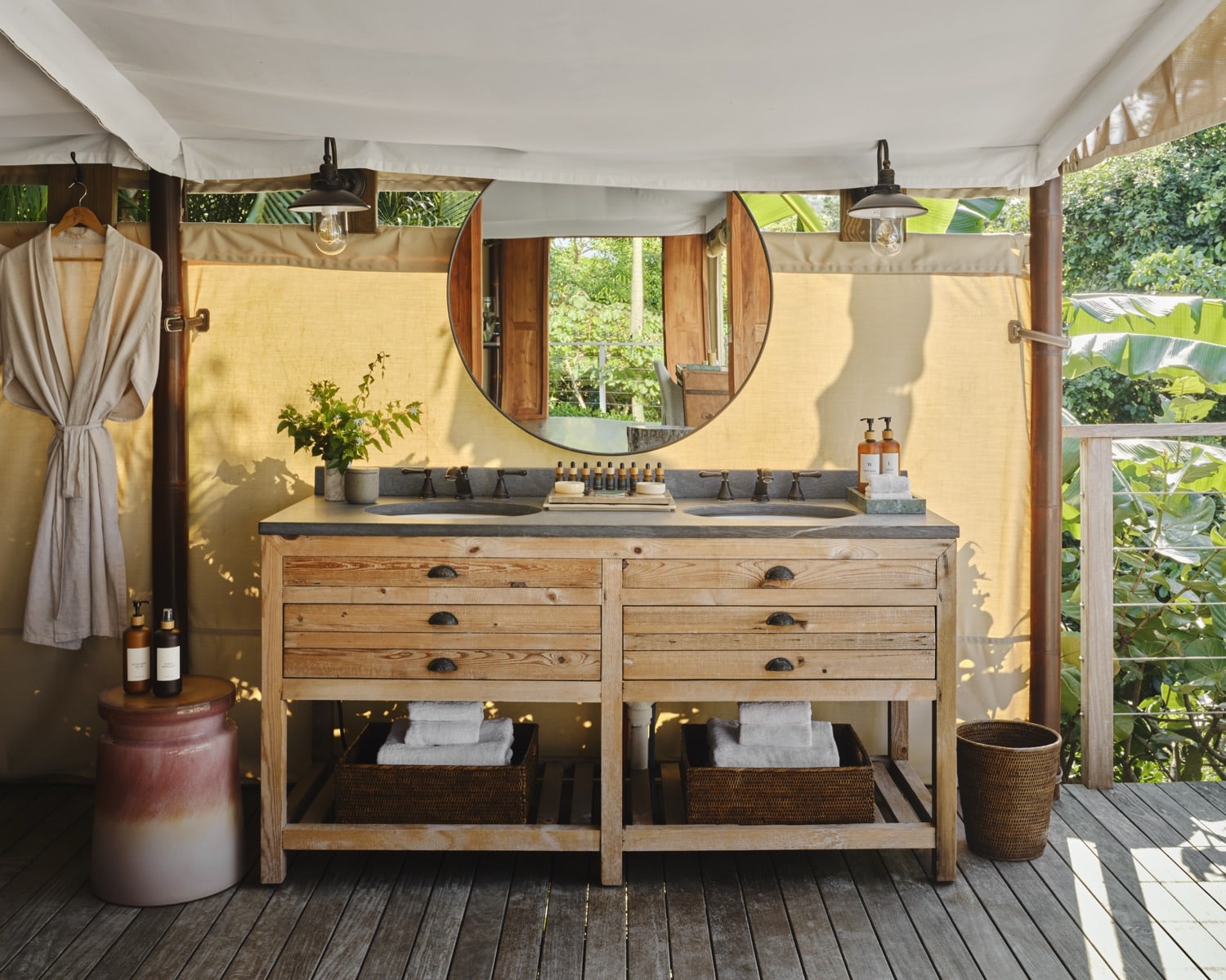 Wooden double sink with a round mirror under a tent-style canopy