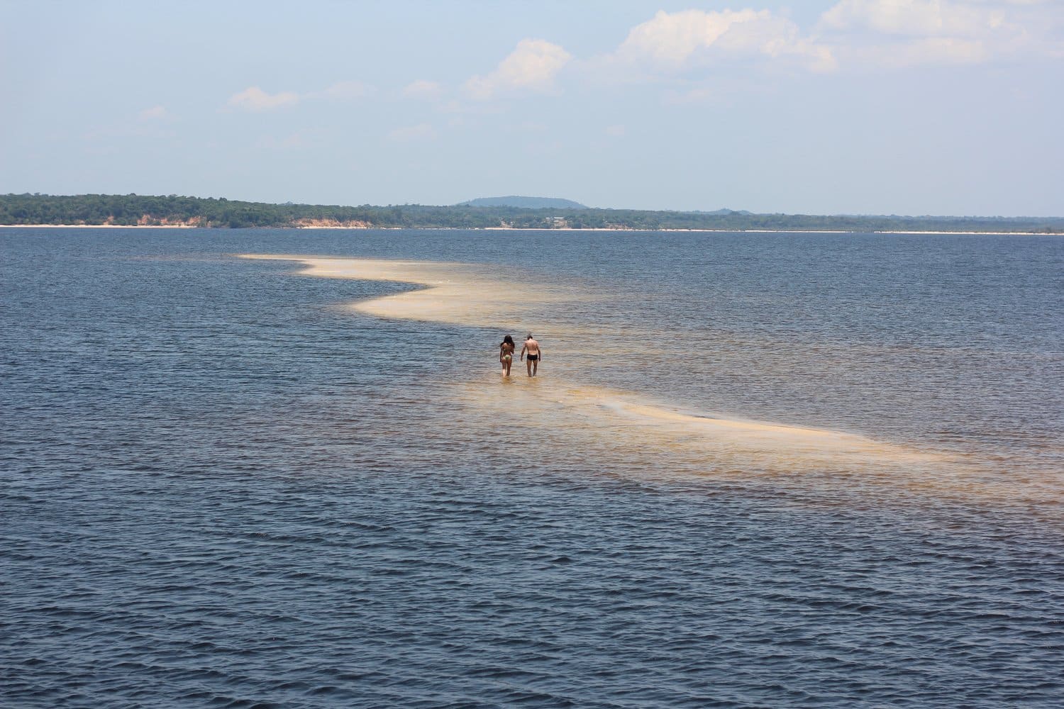 Zwei Reisende gehen über eine helle Sandbank mitten im Fluss