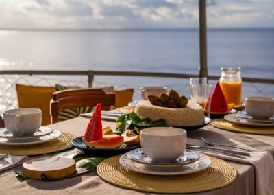 A breakfast table set with watermelon and fresh juice on the deck of the Tupaiú