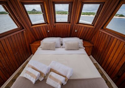 The Tupaiú's master cabin, featuring a double bed and floor-to-ceiling panoramic windows overlooking the river