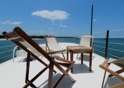 Wooden lounge chairs on the Tupaiú's sun deck under a blue sky