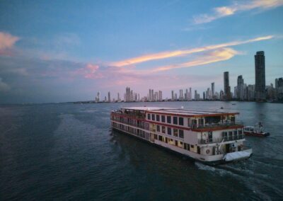 Die AmaMelodia im Abendrot vor der Skyline von Cartagena, längsseits ein Lotsenboot