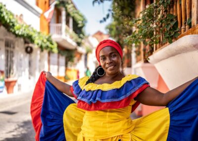 A woman in traditional dress in the colors of Colombia in an alley in Cartagena