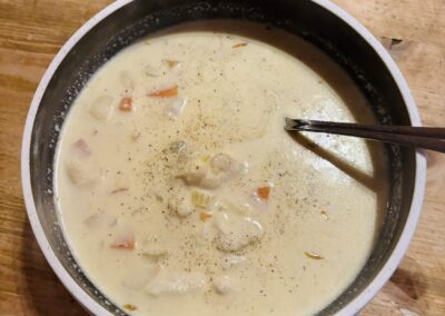 Cremige Fischsuppe mit Kabeljau und Gemüse in einem Topf auf einem Holztisch auf Støtt