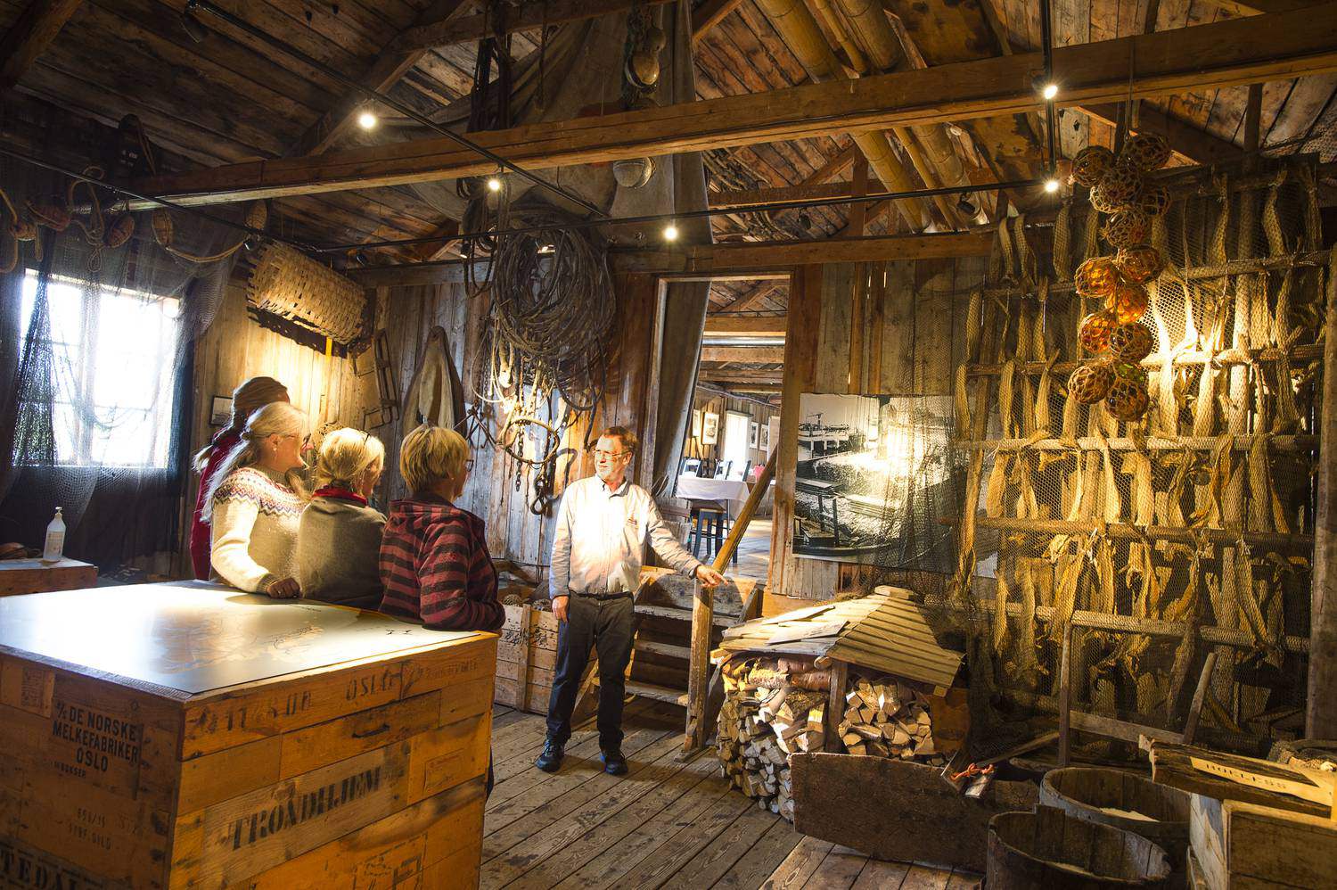 Guide erklärt Besuchern im Fischereimuseum von Støtt Trockenfisch und altes Fanggerät