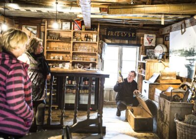 Gäste im historischen Kaufladen Gammelbutikken auf Støtt zwischen alten Regalen