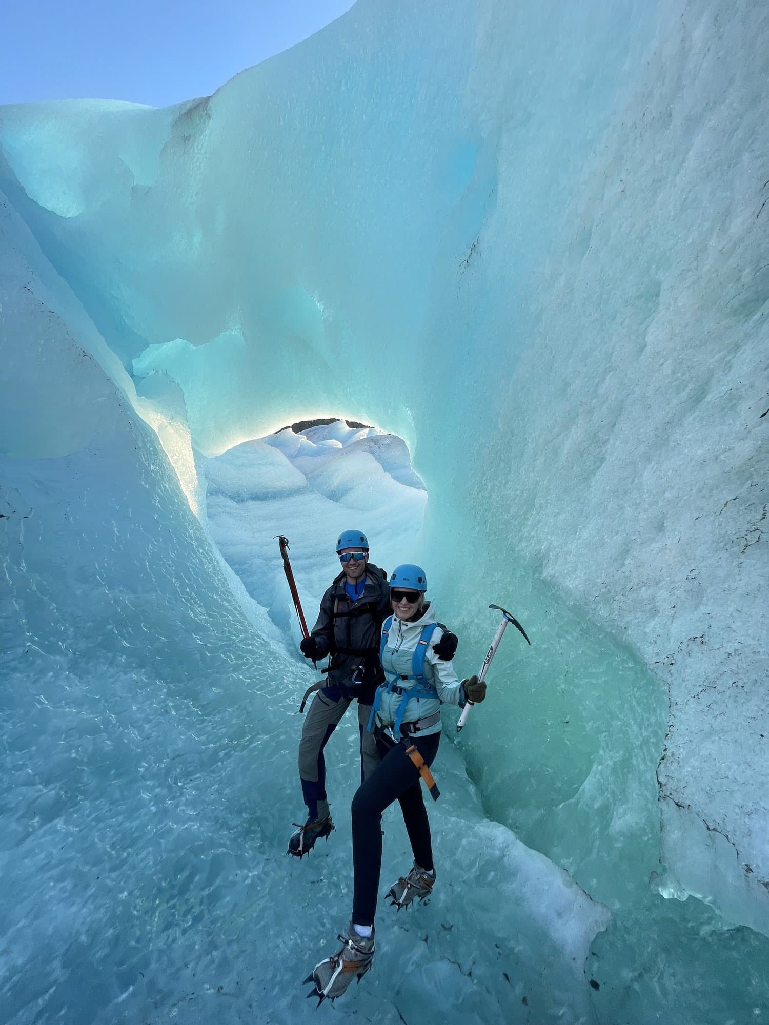 Person mit Helm und Eispickel steht in einer türkis leuchtenden Spalte im Svartisen-Gletscher