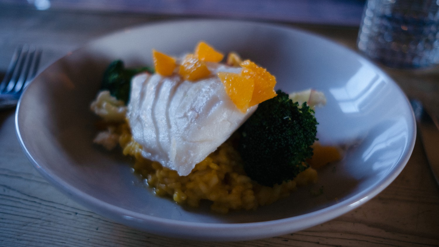 Angerichtetes Kabeljaufilet auf Safranrisotto mit Brokkoli auf hellem Teller