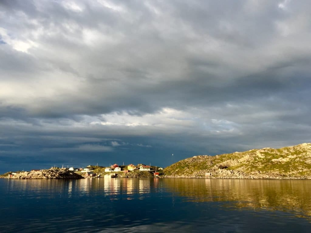 Die dicht beieinander stehenden Häuser der Insel Myken auf dem Fels, vom Wasser aus gesehen