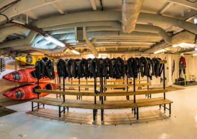 Mudroom mit aufgehängten Expeditionsjacken, Bänken und Kajaks an Bord