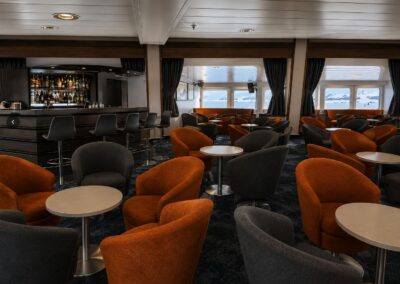 Lounge mit orangefarbenen Sesseln und Panoramafenstern für Vorträge an Bord